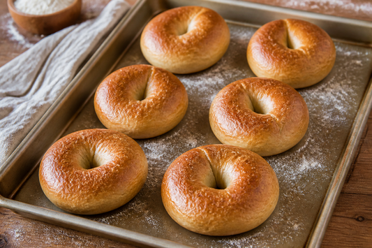 Freshly baked homemade bagels with golden crusts arranged on a baking pan
