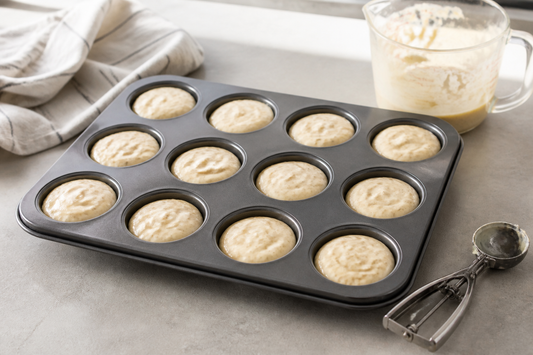 Muffin pan with evenly portioned batter and consistent filling tools ready for baking
