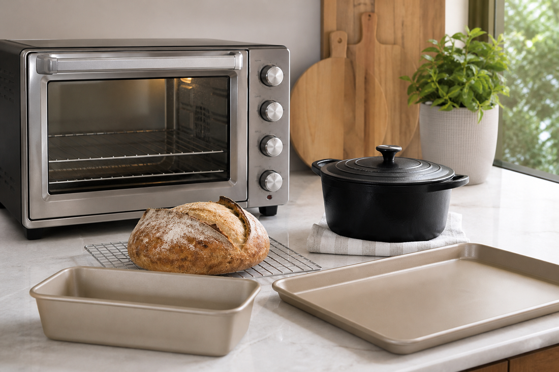 Countertop oven beside a sourdough boule, covered Dutch oven, loaf pan, and sheet pan