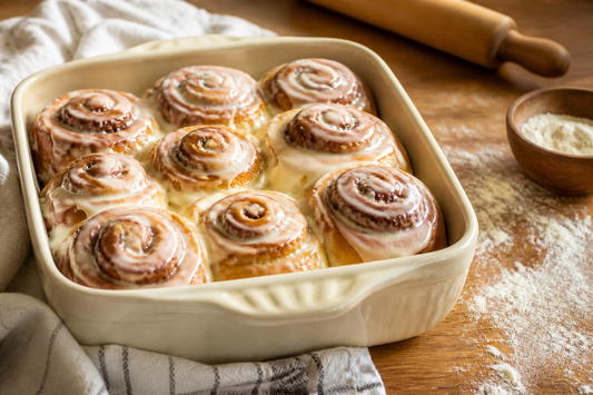 Freshly baked cinnamon rolls with white glaze in a ceramic baking dish